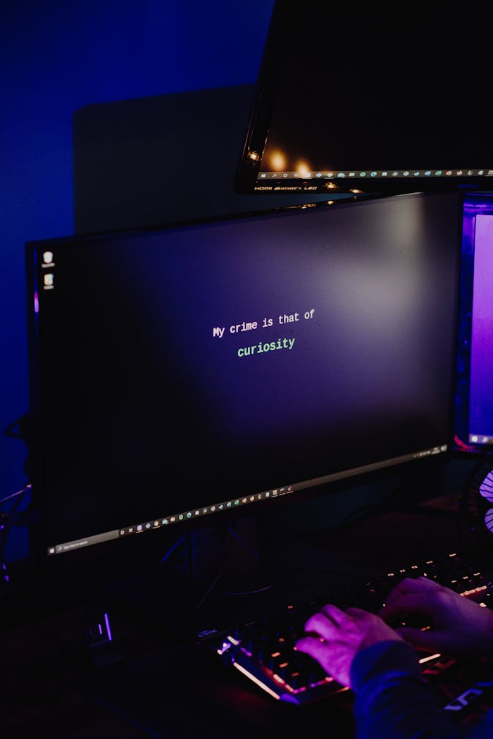 A hacker typing on a keyboard in a dimly lit room, highlighting cybersecurity threats at night.